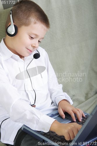 Image of Smiling boy in headset working on laptop