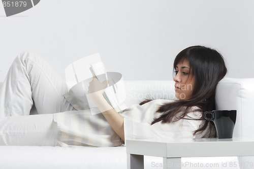 Image of Brunette with book laying down on back