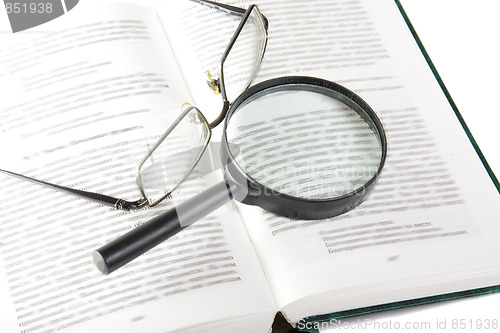 Image of Magnifier and eyeglasses on open book
