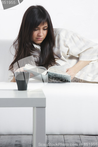Image of Brunette woman reading on sofa