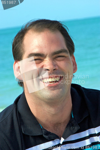 Image of handsome man laughing at beach