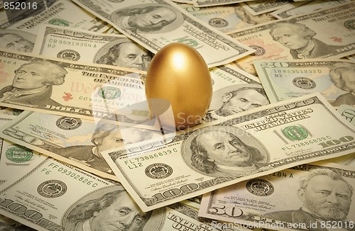 Image of Gold nest egg on a layer of cash of various American banknote de