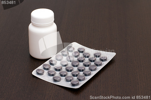 Image of White vial, black pills