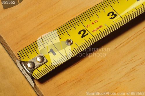 Image of Yellow tape measure measuring a piece of wood