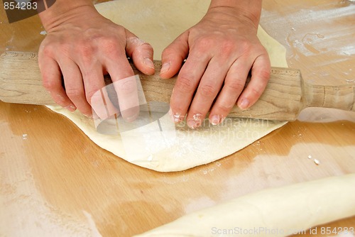 Image of Hands on rolling pin over dough