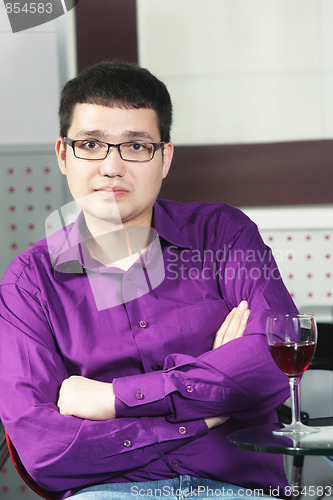 Image of Guy in cafe with glass of wine arms folded