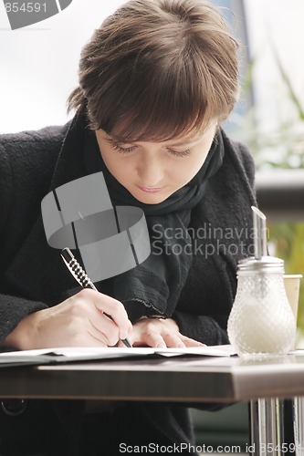 Image of Woman in black coat writing