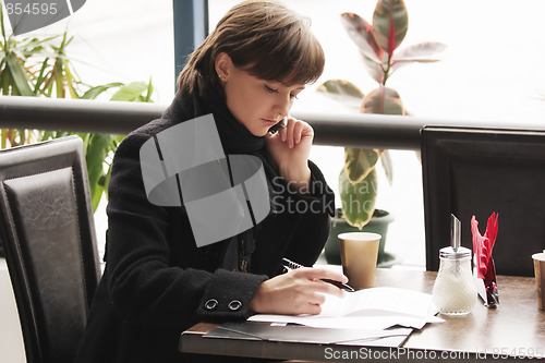 Image of Woman in black coat working in cafe