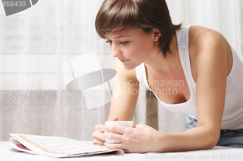 Image of Woman with cup reading paper