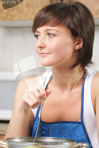 Image of Cute woman steering food in pan