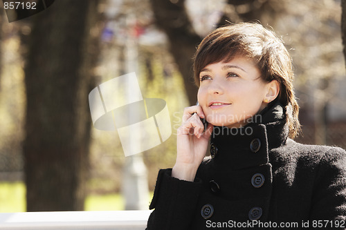 Image of Smiling woman in park with cellphone