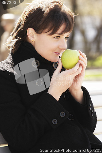 Image of Woman in black smelling apple