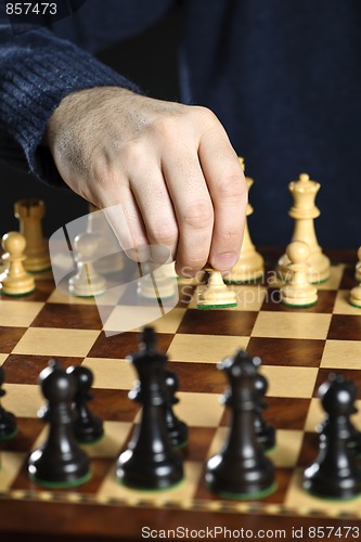 Image of Hand moving pawn on chess board