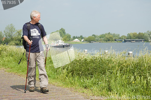 Image of Senior man doing a Nordic Walk on a sunny day.