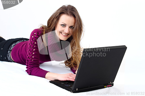 Image of lying and smiling attractive woman with a laptop