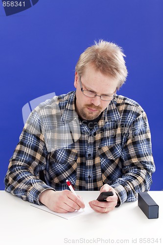 Image of Man writes notes at his office desk