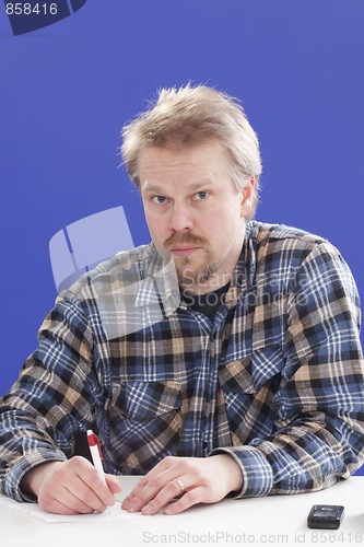 Image of Man writes notes at his office desk