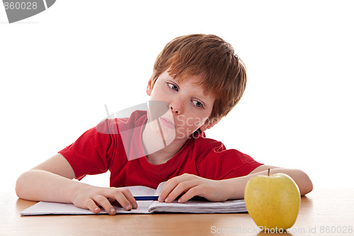 Image of boy studying and distracted with an apple