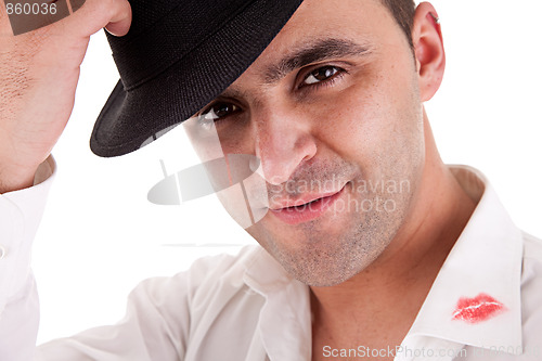 Image of seductive man greeting with his hat, the shirt with lipstick mark