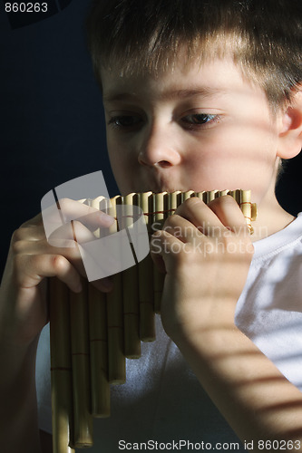 Image of Boy playing panflute in darkness