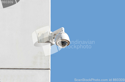 Image of surveillance camera at a white wall with blue sky background