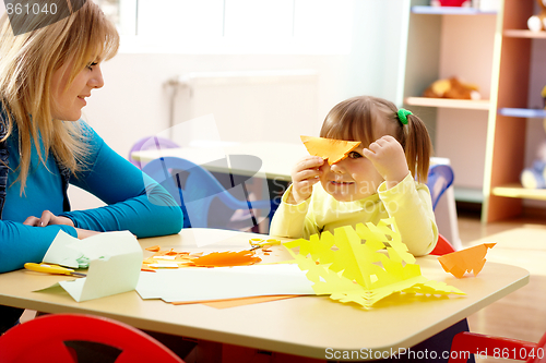 Image of Teacher and little girl play with color paper