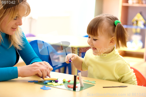 Image of Teacher and little girl play with plasticine