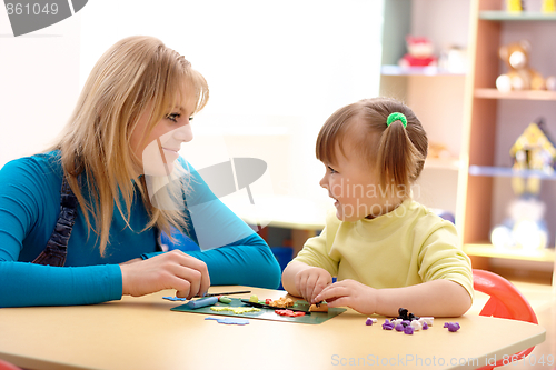 Image of Teacher and little girl play with plasticine