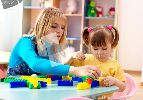 Image of Teacher and preschooler play with building bricks