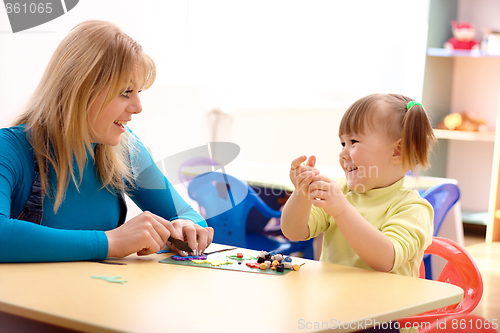 Image of Teacher and little girl play with plasticine