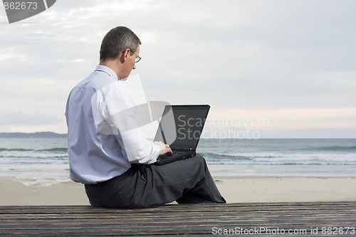 Image of Businessman working with laptop on a beach