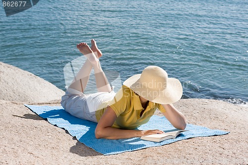 Image of Woman reading at the sea