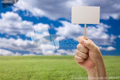 Image of Blank Sign in Fist Over Grass Field and Sky