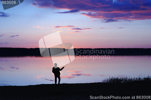 Image of The fisherman with a fishing tackle at lake on a sunset