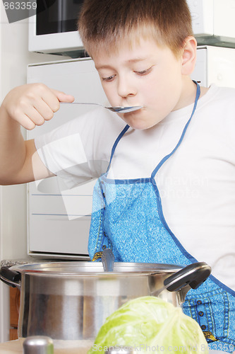 Image of Boy testing soup from pan