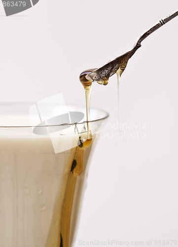 Image of Honey poured into milk with spoon