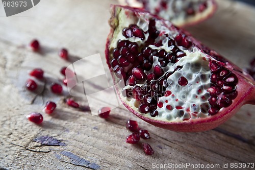 Image of Pomegranate with arils on wooden board