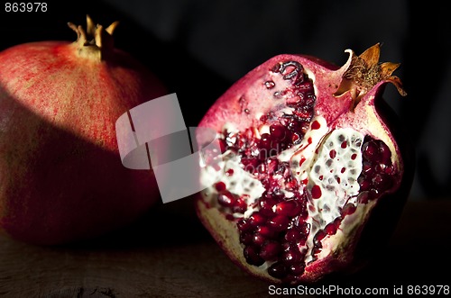 Image of Pomegranate with arils on wooden board