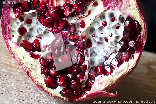 Image of Pomegranate with arils on wooden board