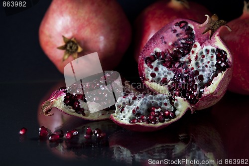 Image of Sliced Pomegranate with arils on black glass