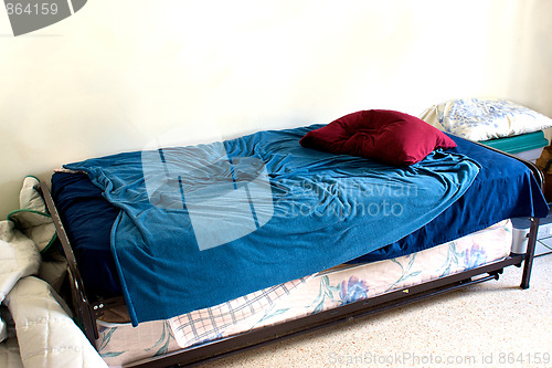 Image of small used bed in white room