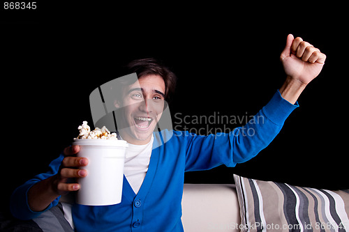 Image of happy young man, with popcorn watching