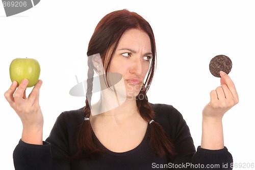 Image of woman choosing between chocolate cookies and apple