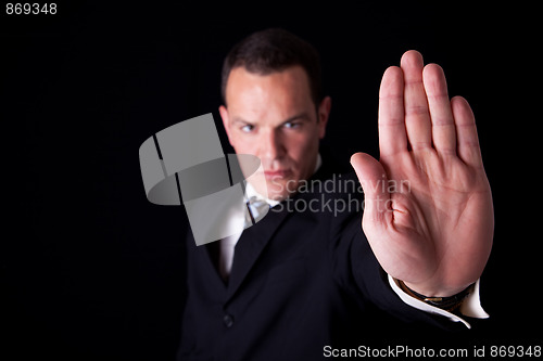 Image of Businessman with his hand raised in signal to stop, isolated on black background, Studio shot