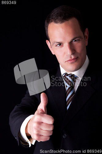 Image of businessman giving consent, with thumb up, isolated on black background. Studio shot.