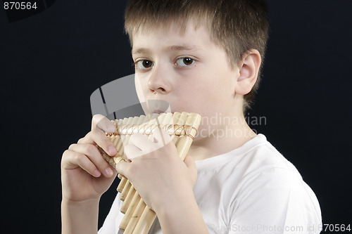 Image of Boy in white shirt playing bamboo panflute