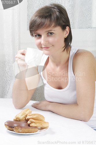 Image of Smiling woman drinking tea with cakes