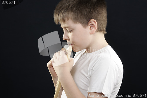Image of Kid in white playing panflute sideview