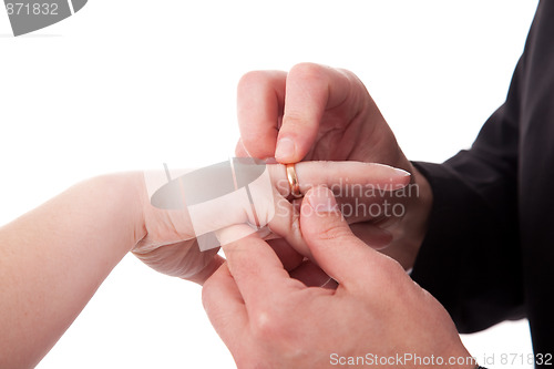 Image of hand of a man putting a ring on the hand of a woman