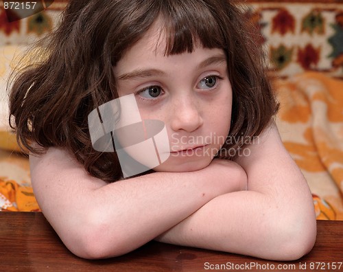 Image of Serious cute little girl rests her head on crossed arms